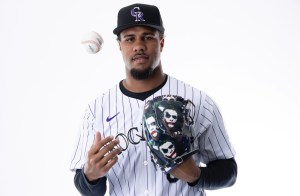 Jaden Hill wears a Rockies uniform and tosses a ball in the air. On his left hand is a glove with The Joker imprinted on it